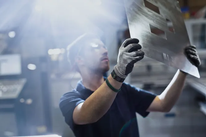 Mitarbeiter im Metallgewerbe begutachtet eine Metallplatte