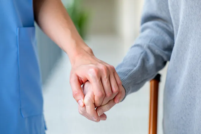 Pflegerin hält die Hand einer Seniorin