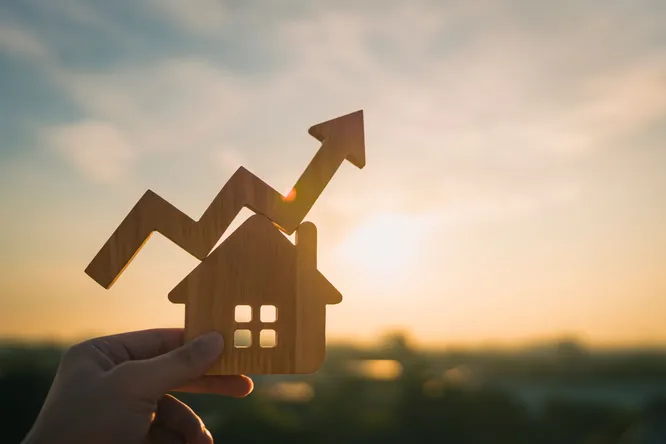 Hand hält ein kleines Haus aus Holz